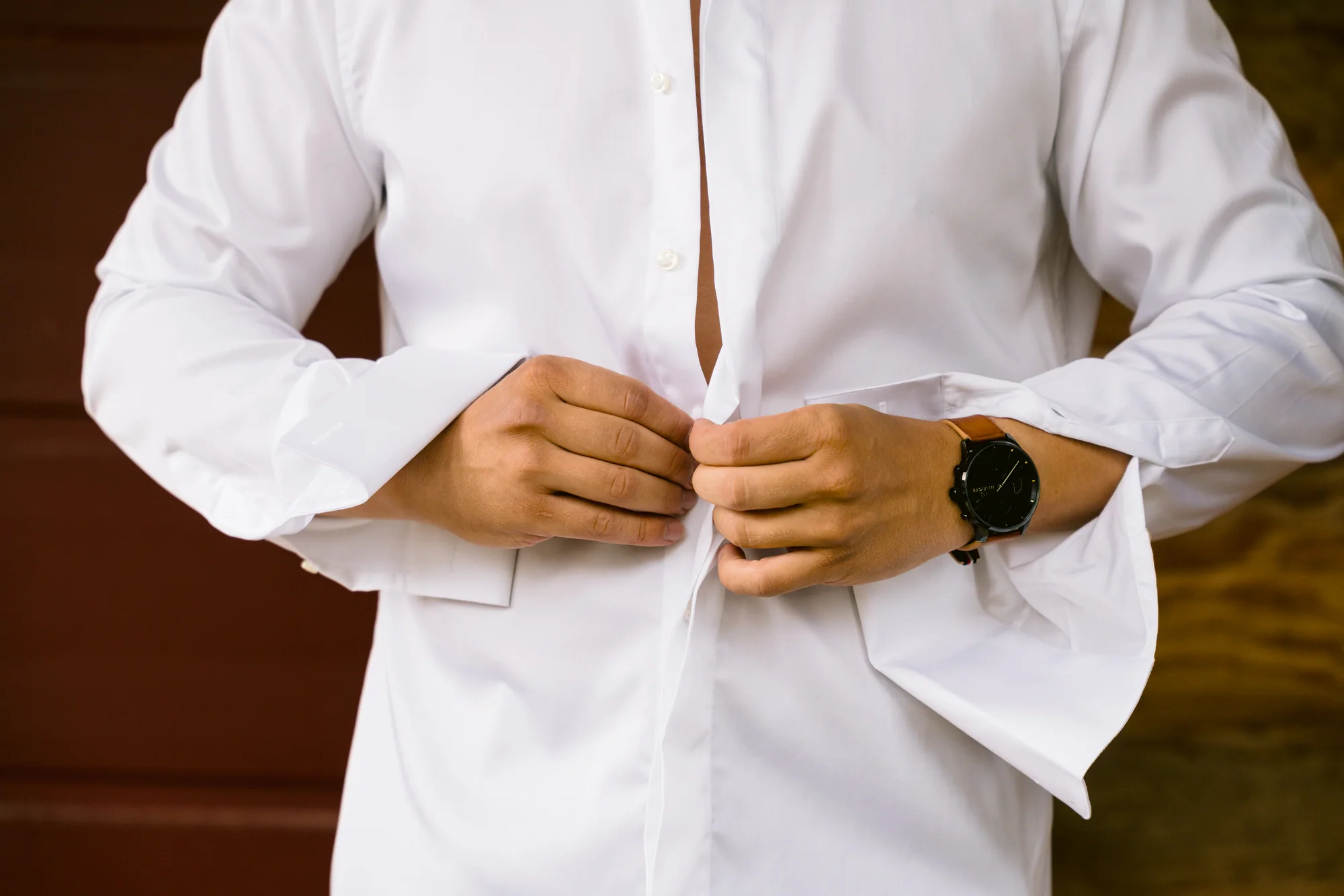 Les mains du marié boutonnent sa chemise