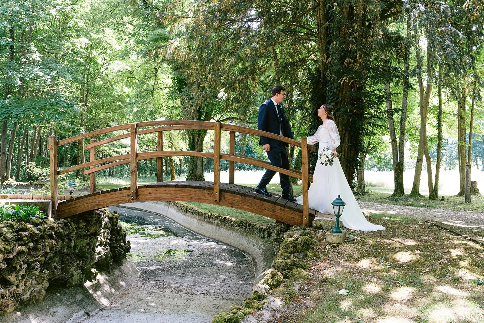 Les mariés se font face sur une petite passerelle en bois, entourée d’arbres.