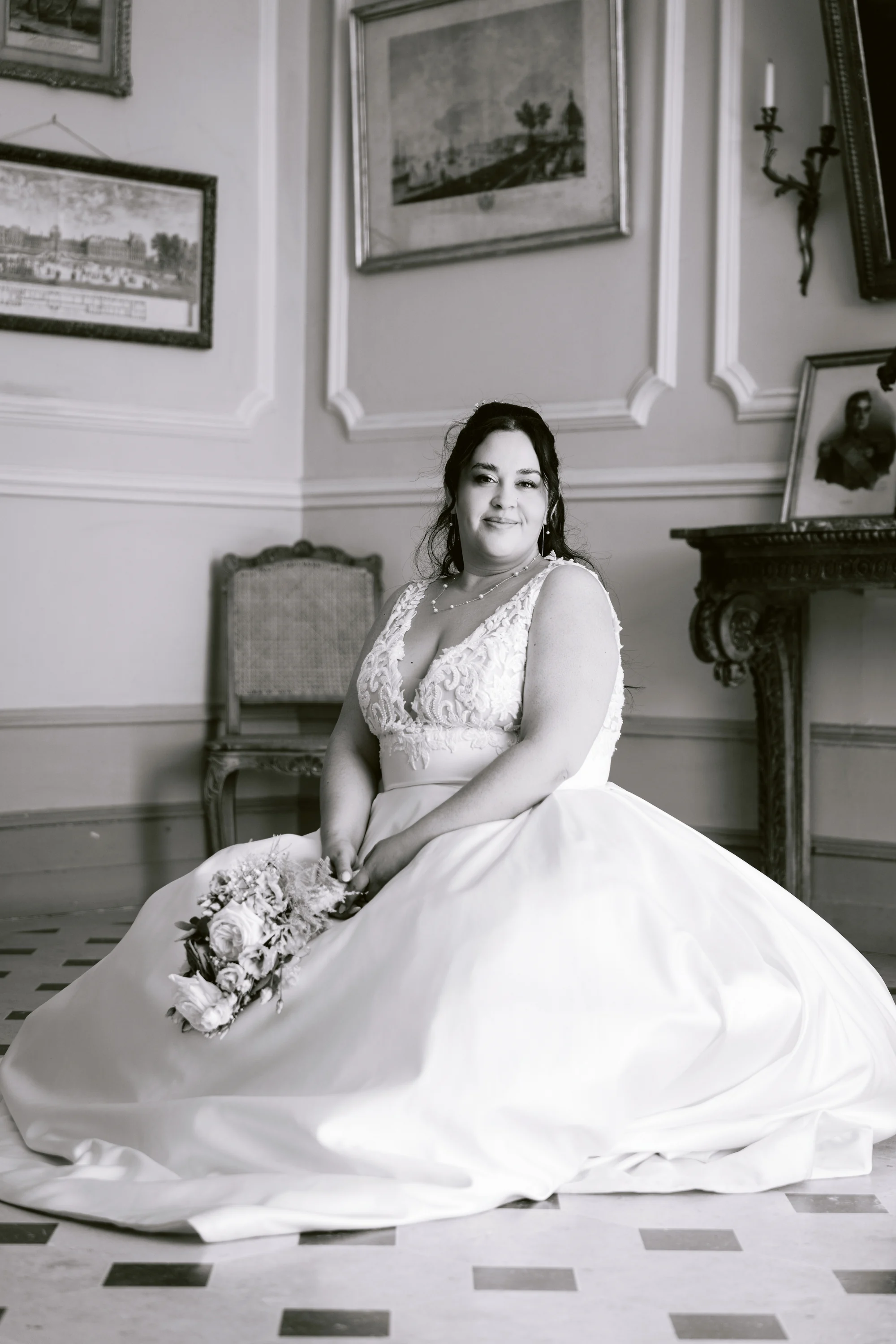 La mariée est assise dans une pièce ornée de moulures, en noir et blanc.