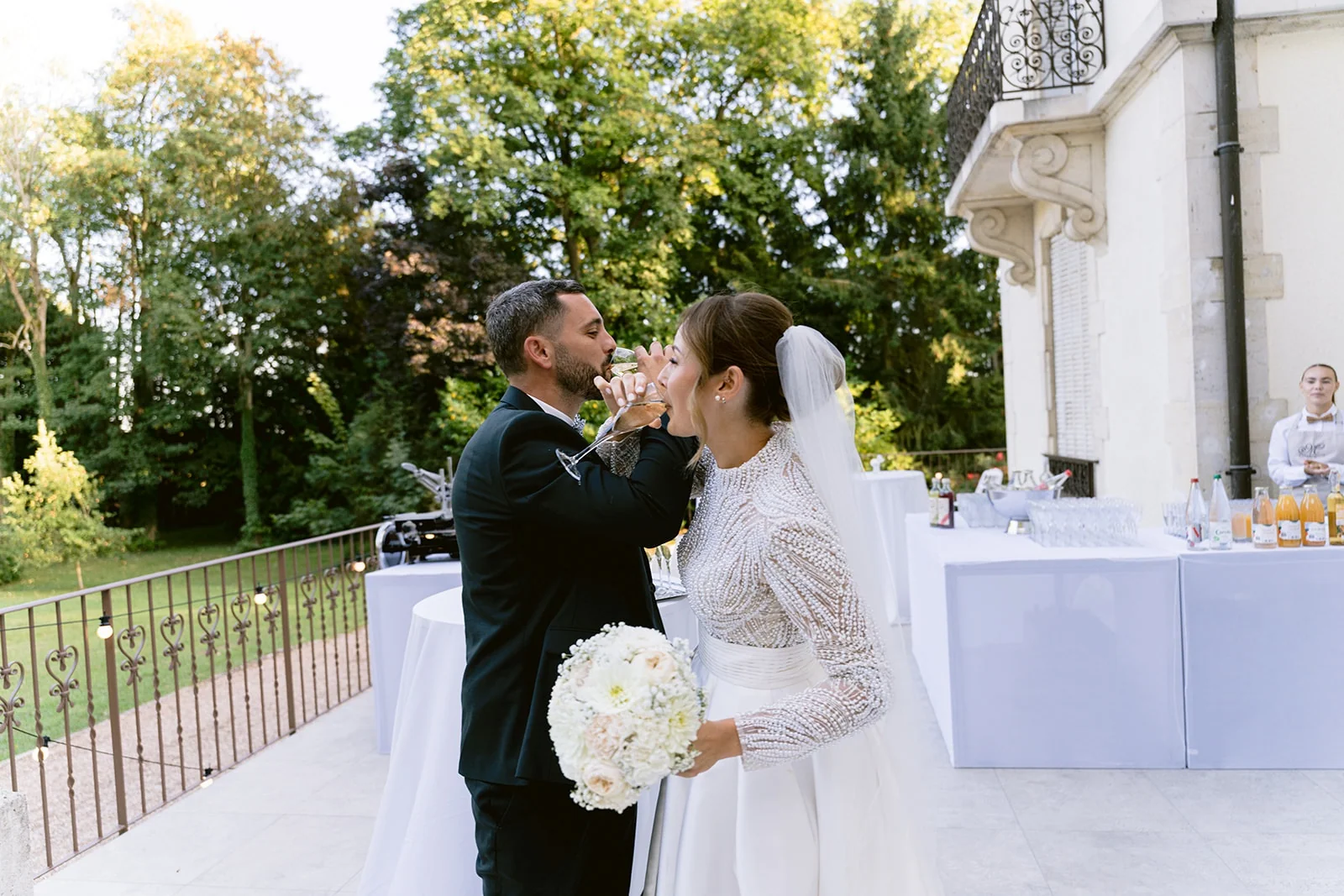Sur la terrasse, le marié rapproche son visage de celui de la mariée en tenant sa tête entre ses mains.