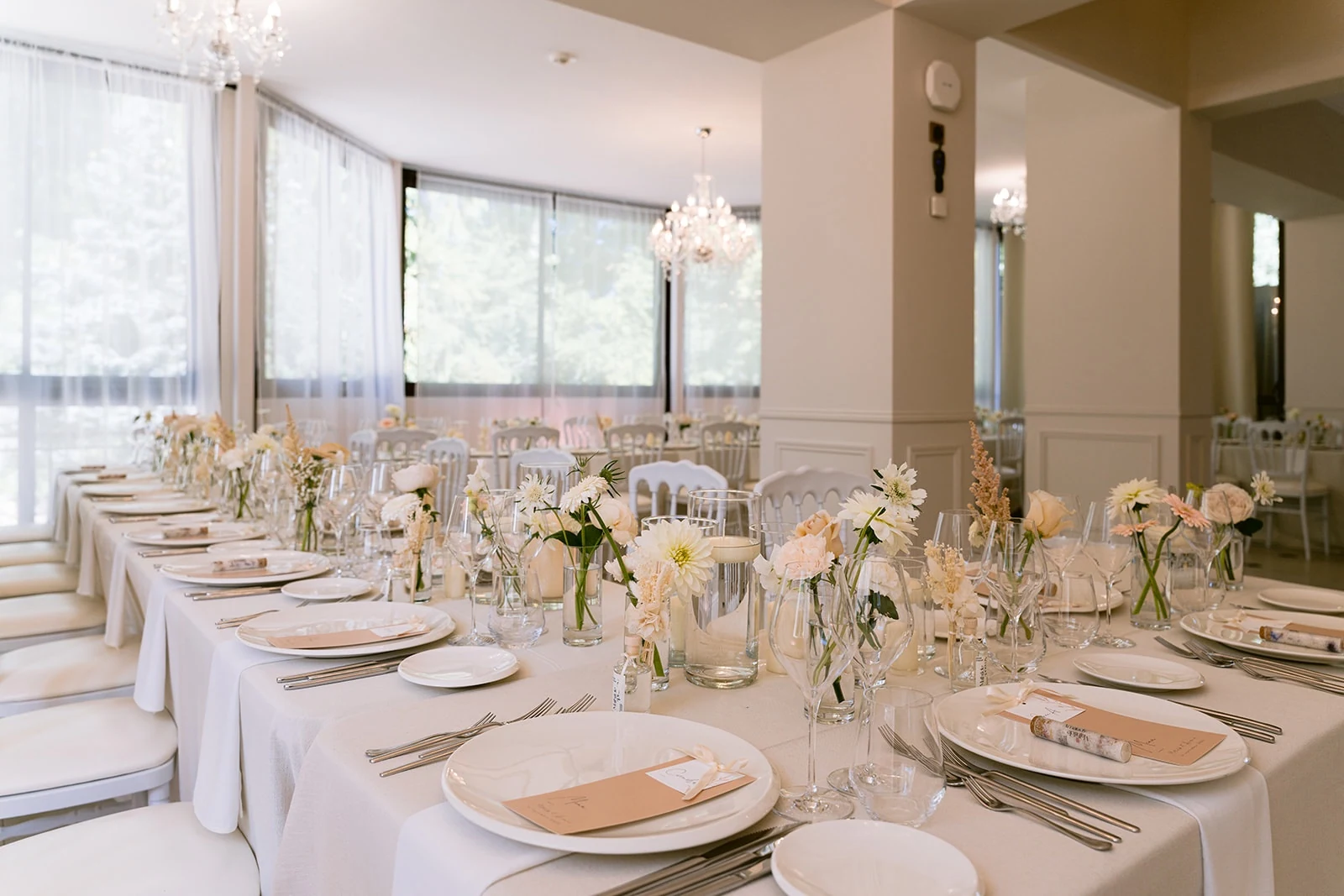 Les tables de réception sont dressées sous les lustres, près des grandes fenêtres.