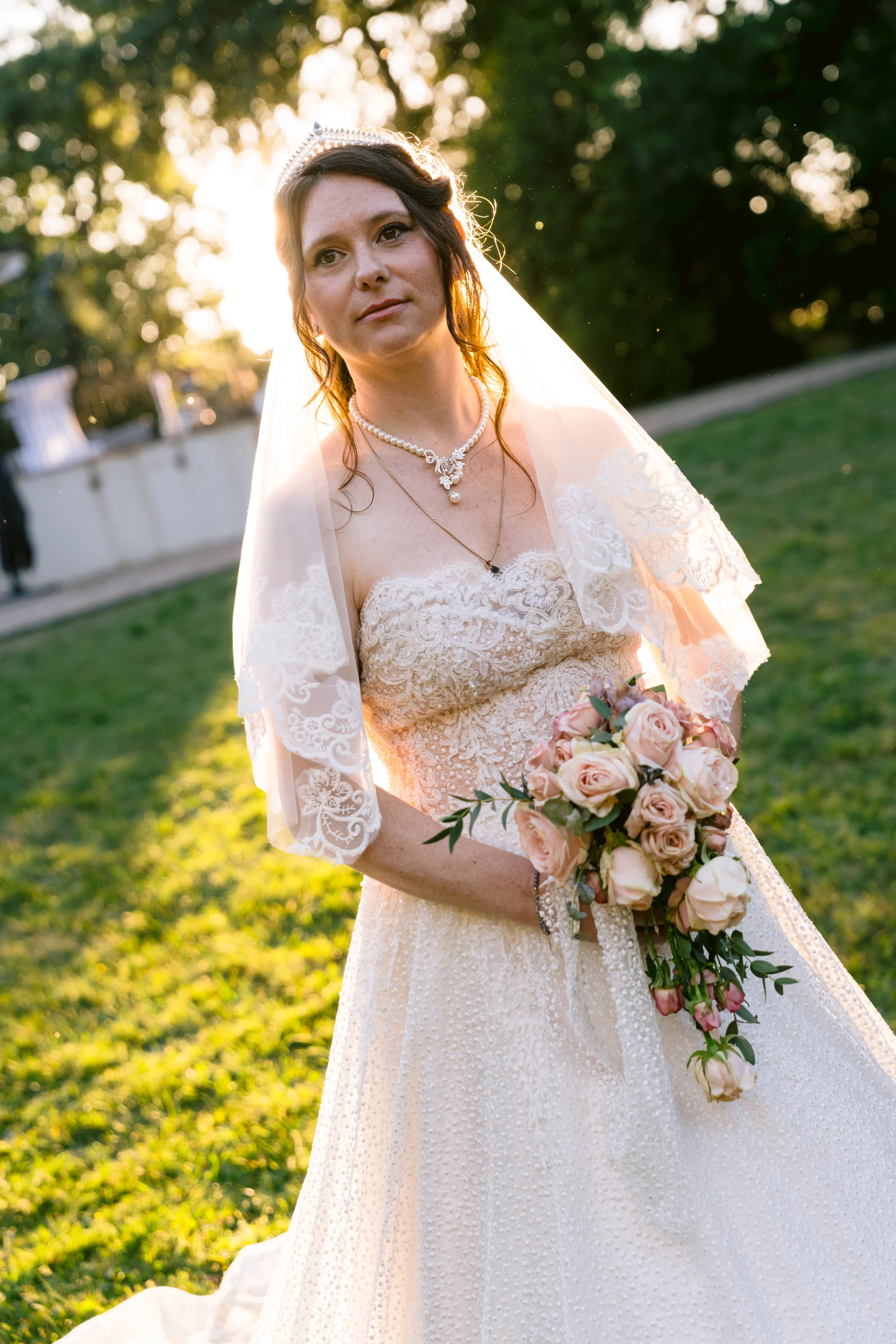 La mariée tient son bouquet dans la lumière dorée d’un jardin.