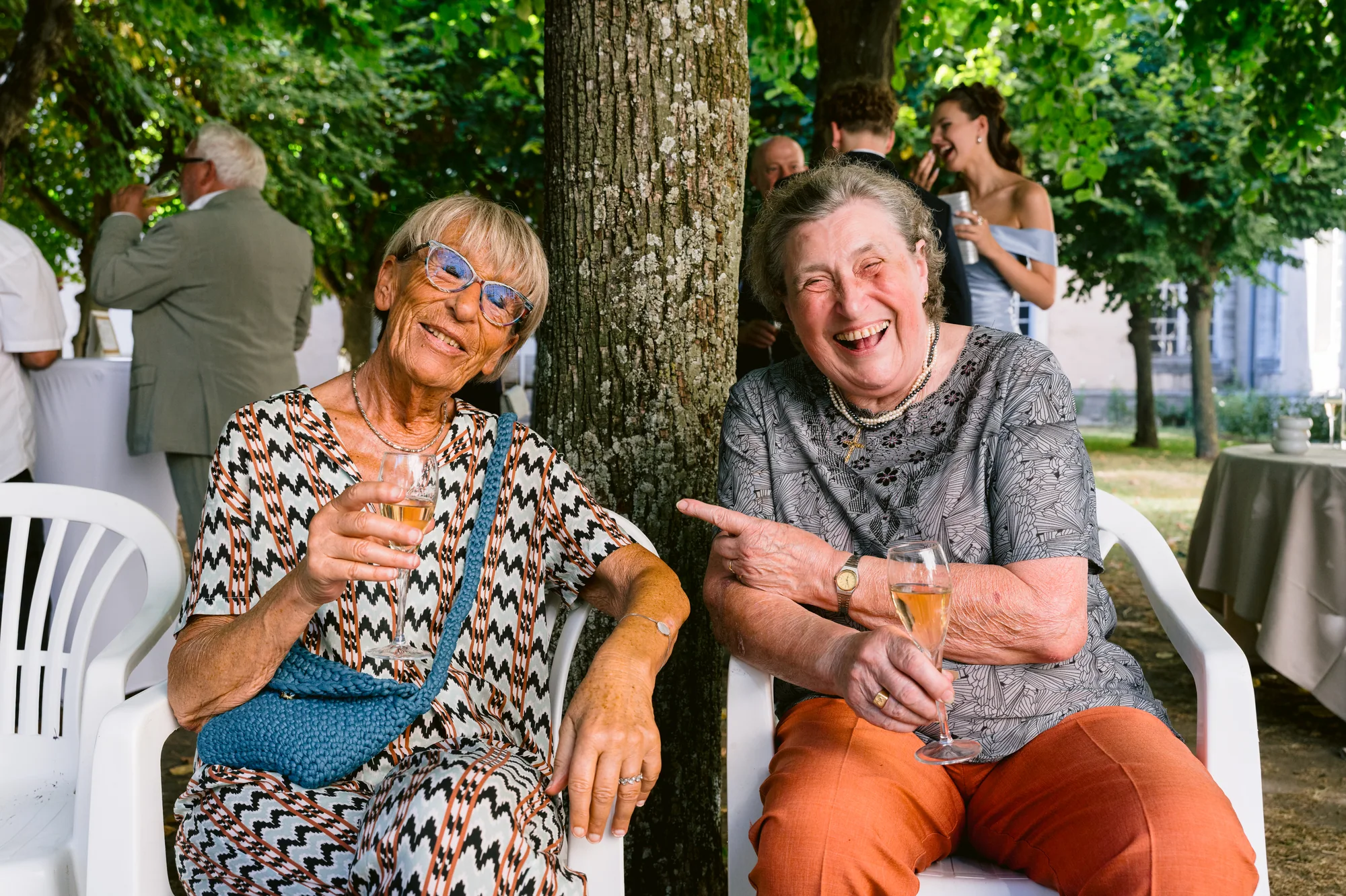 Deux invités rient à l'ombre des arbres