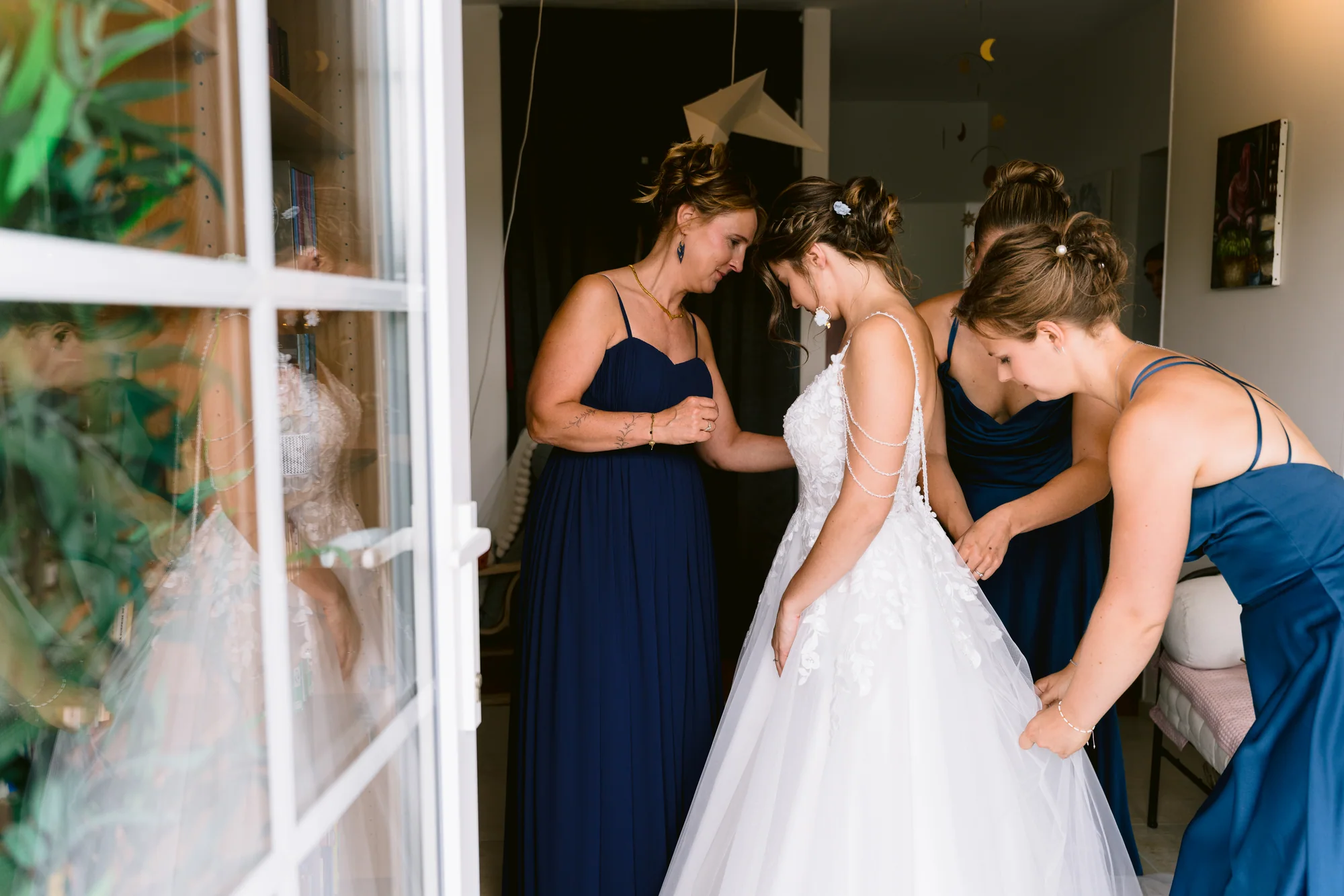 Les proches aident la mariée à enfiler sa robe