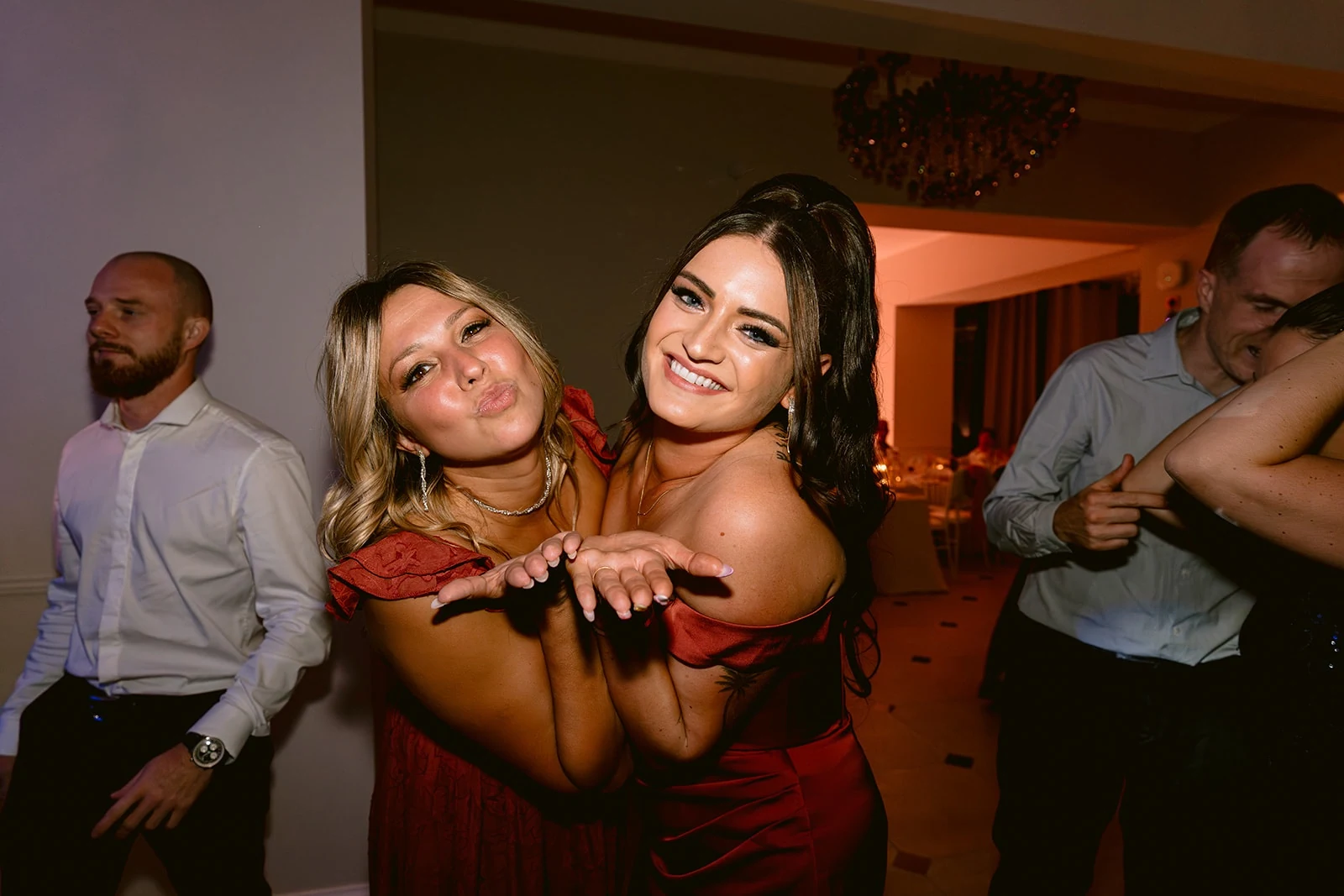 Deux invitées sourient et tendent les mains vers l’appareil sur la piste de danse.