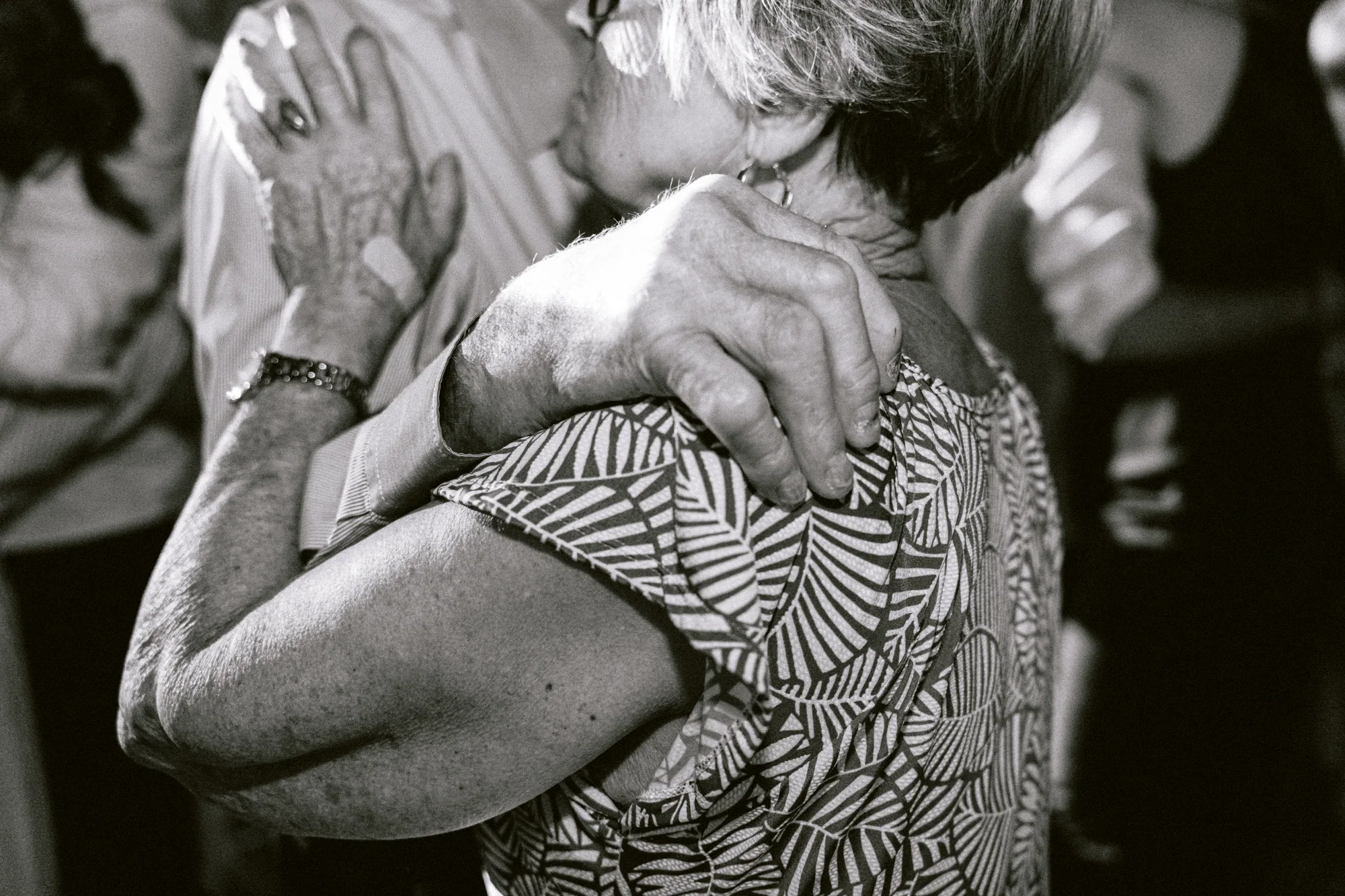 Un couple de proches danse enlacé, en noir et blanc