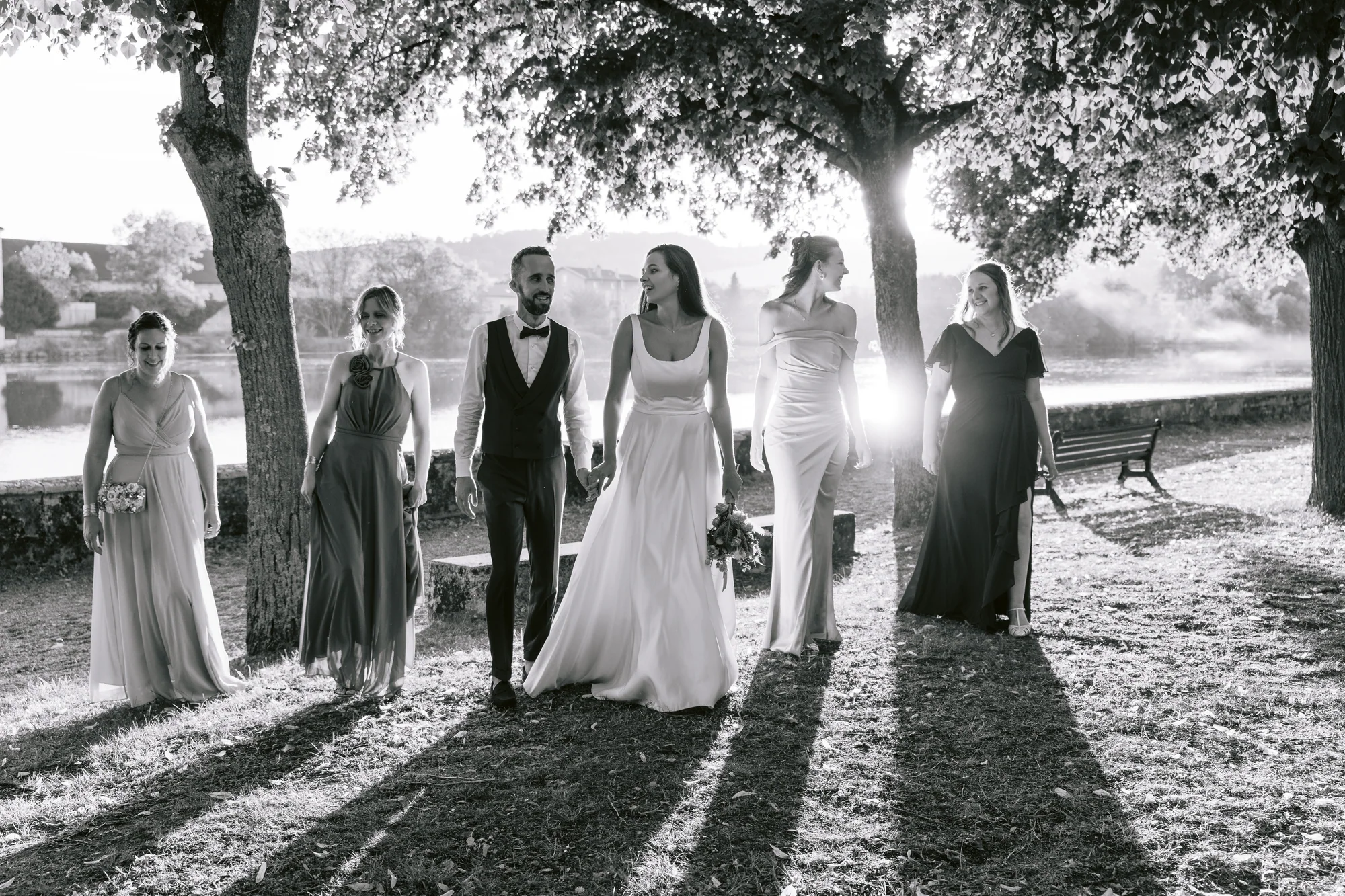 Les mariés et leurs proches marchent au soleil, en noir et blanc