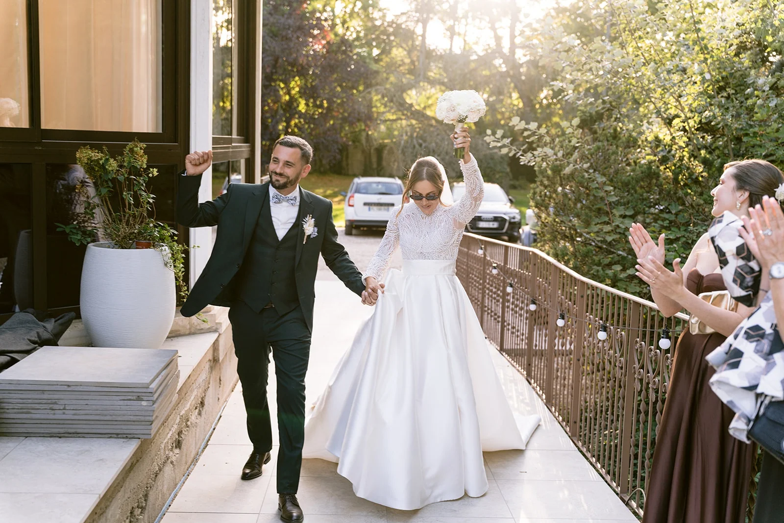 Les mariés arrivent sur la terrasse en levant les bras sous les applaudissements des invités.