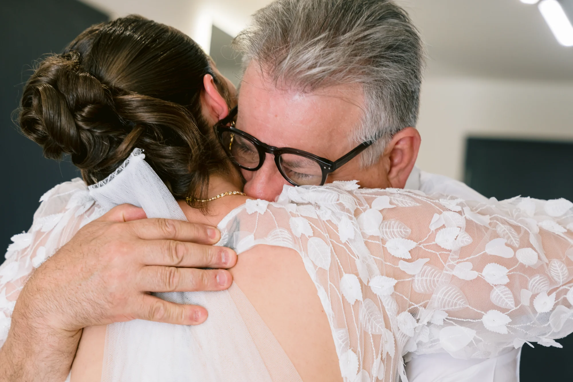 Un proche serre la mariée contre lui, les yeux fermés.