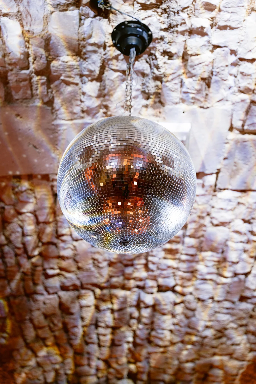 Une boule à facettes est suspendue sous une voûte en pierre éclairée de reflets lumineux.