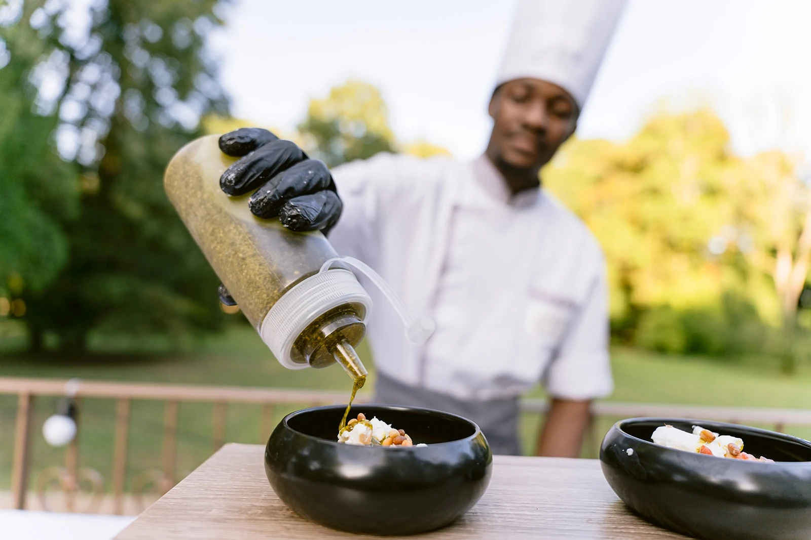 Un cuisinier verse un filet d’assaisonnement dans une petite assiette pendant le cocktail.