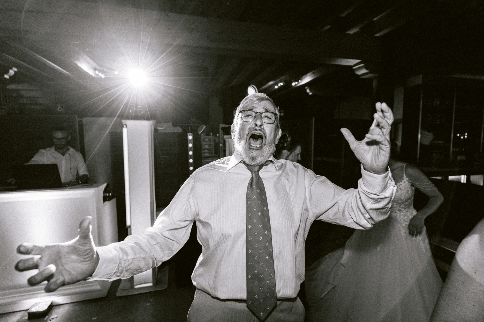 Un invité chante, les bras ouverts, en noir et blanc