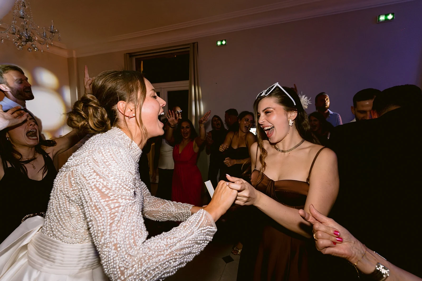 La mariée danse en riant avec une invitée pendant la soirée.