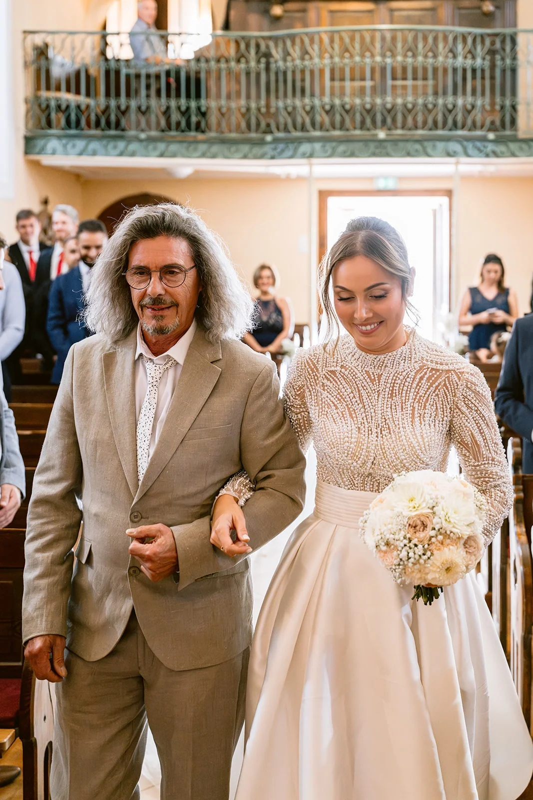 La mariée entre dans l’église au bras d’un proche, son bouquet à la main.