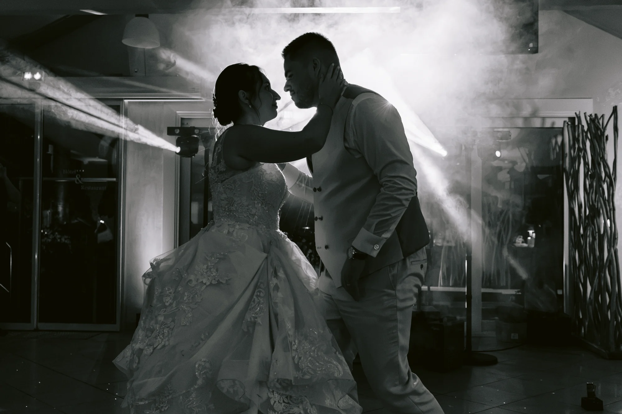 Le couple danse en silhouette devant les lumières de la piste, en noir et blanc.